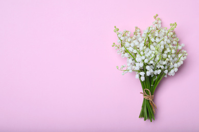 Photo of Beautiful lily of the valley flowers on pink background, top view. Space for text