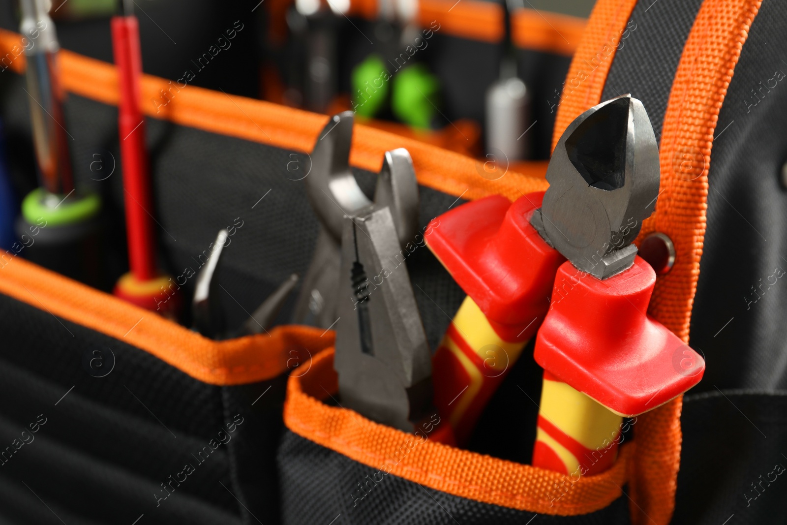 Photo of Bag with different pliers and other repair tools, closeup. Space for text