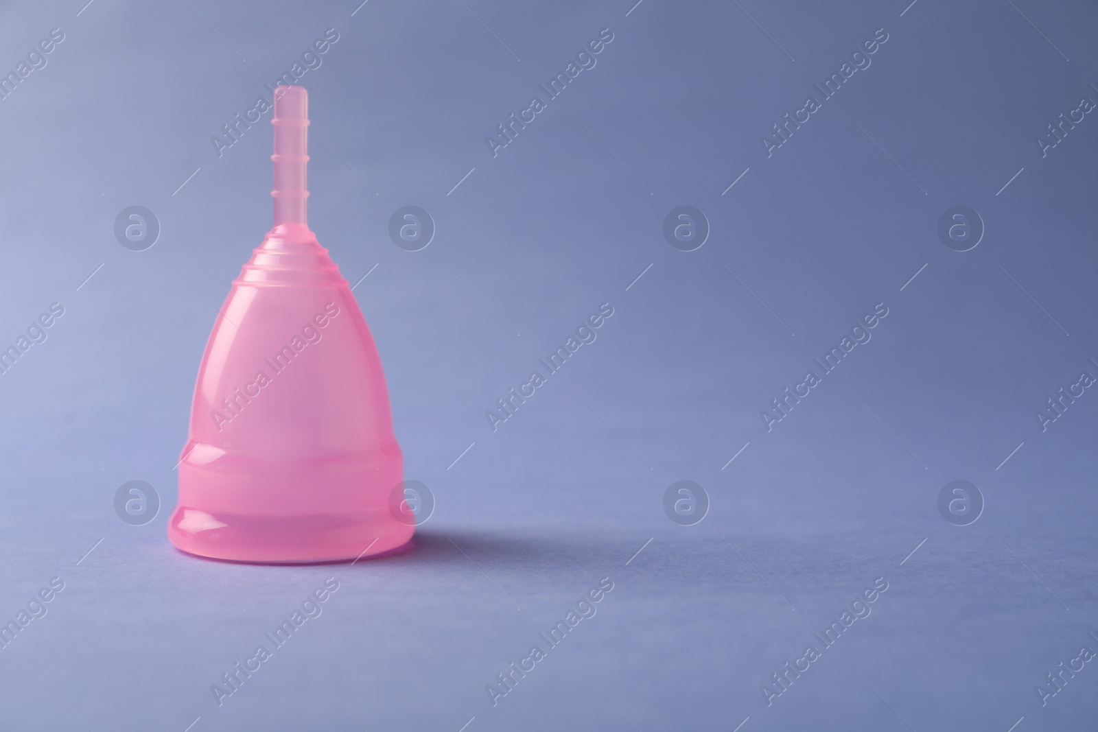 Photo of Menstrual cup on blue background. Space for text