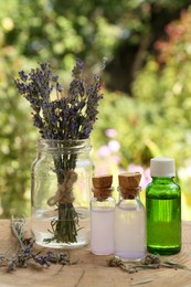 Beautiful lavender flowers and bottles of essential oil on wooden stump