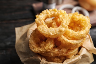 Dishware with homemade crunchy fried onion rings on wooden table, closeup