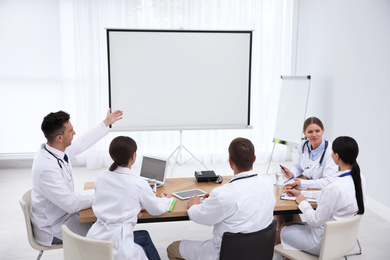 Photo of Team of doctors using video projector during conference indoors