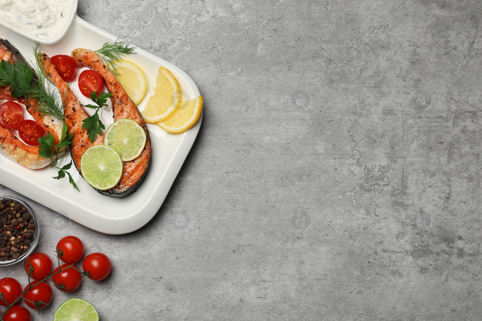 Photo of Tasty grilled salmon steaks and ingredients on light grey table, flat lay. Space for text