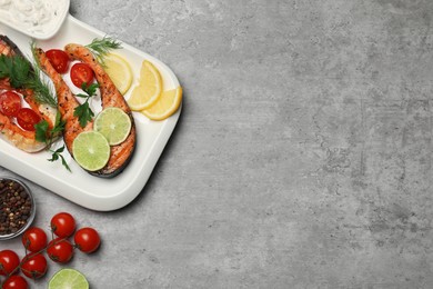 Tasty grilled salmon steaks and ingredients on light grey table, flat lay. Space for text