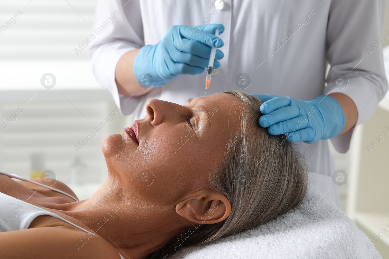 Photo of Doctor giving facial injection to senior woman in clinic, closeup. Cosmetic surgery