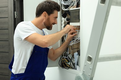 Electrician repairing fuse box with screwdriver indoors