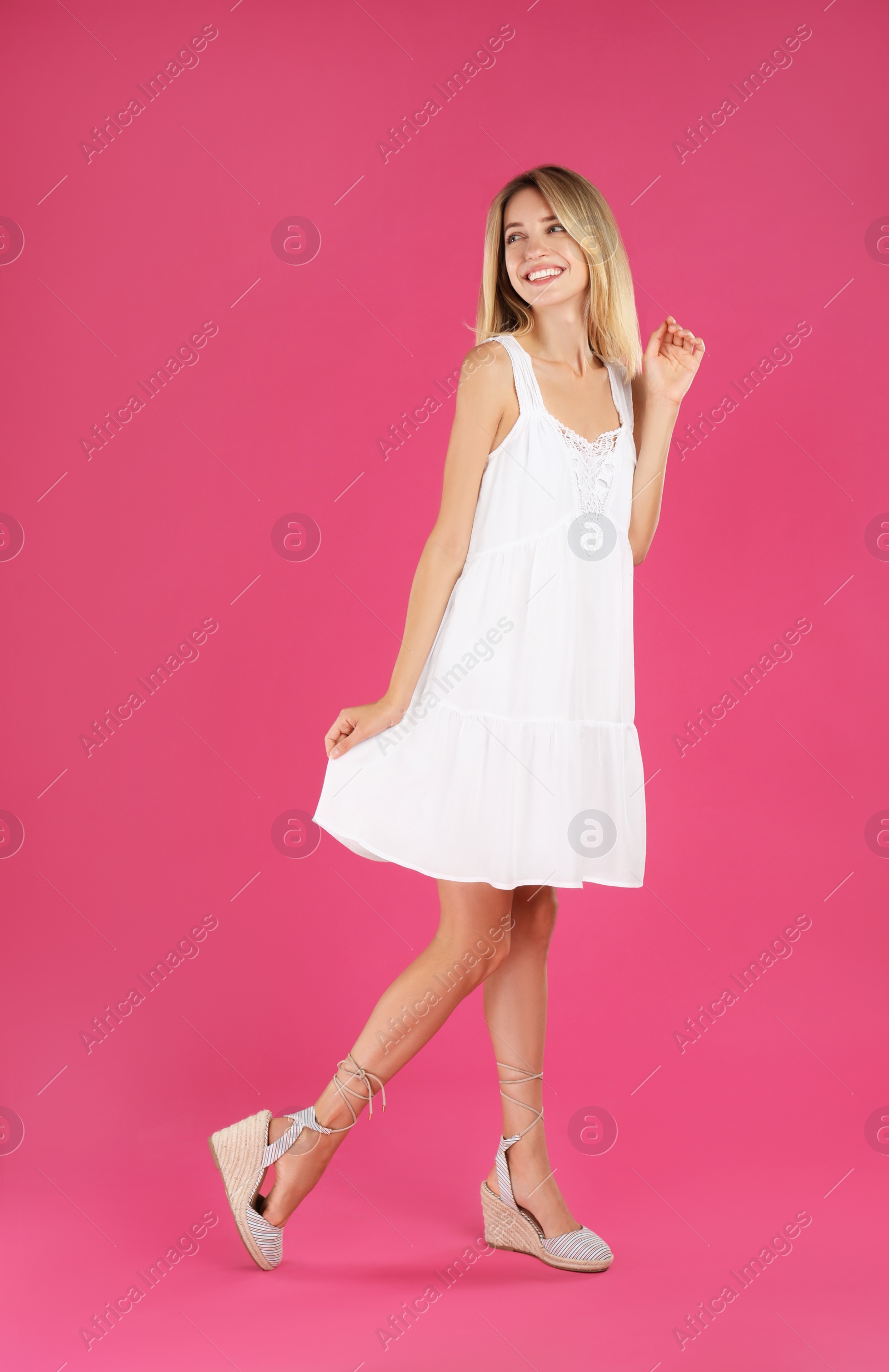 Photo of Young woman wearing stylish white dress on pink background