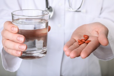 Photo of Doctor holding pills and glass of water, closeup. Anemia concept