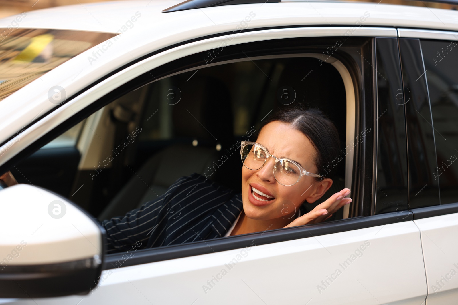 Photo of Stressed driver screaming in her car. Stuck in traffic jam