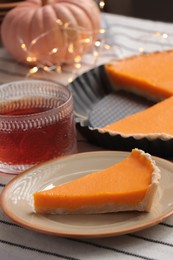 Photo of Piece of fresh homemade pumpkin pie served with tea on table