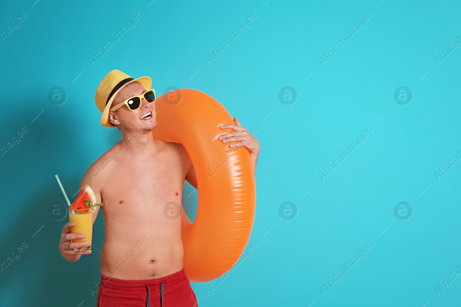 Photo of Shirtless man with inflatable ring and glass of cocktail on color background