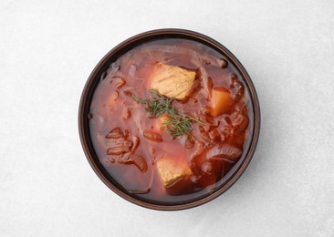 Bowl of delicious borscht on white table., top view