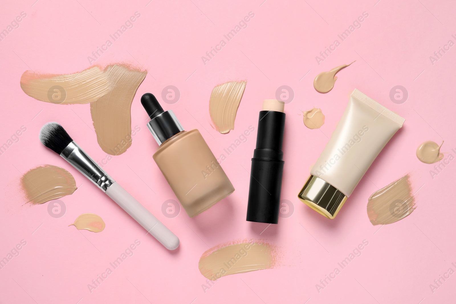 Photo of Foundations and makeup brush on pink background, flat lay
