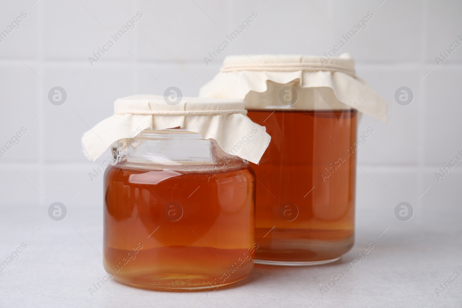 Photo of Tasty kombucha in glass jars on white table