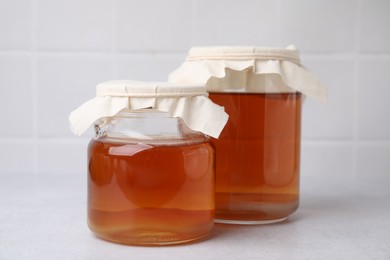 Tasty kombucha in glass jars on white table