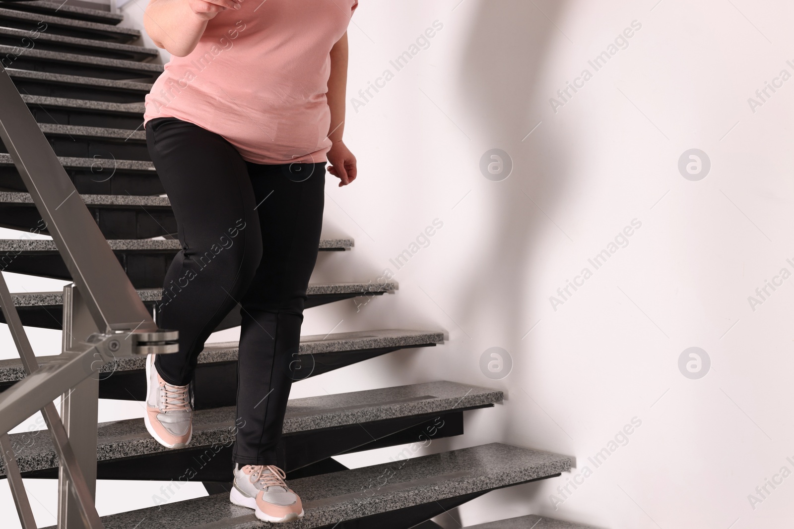 Photo of Overweight mature woman running downstairs indoors, closeup. Space for text