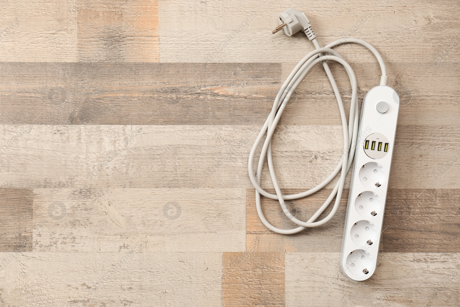 Photo of Extension cord on wooden floor, top view with space for text. Electrician's equipment