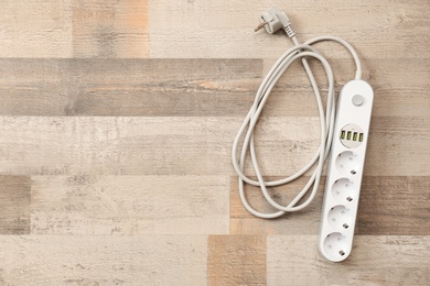 Extension cord on wooden floor, top view with space for text. Electrician's equipment