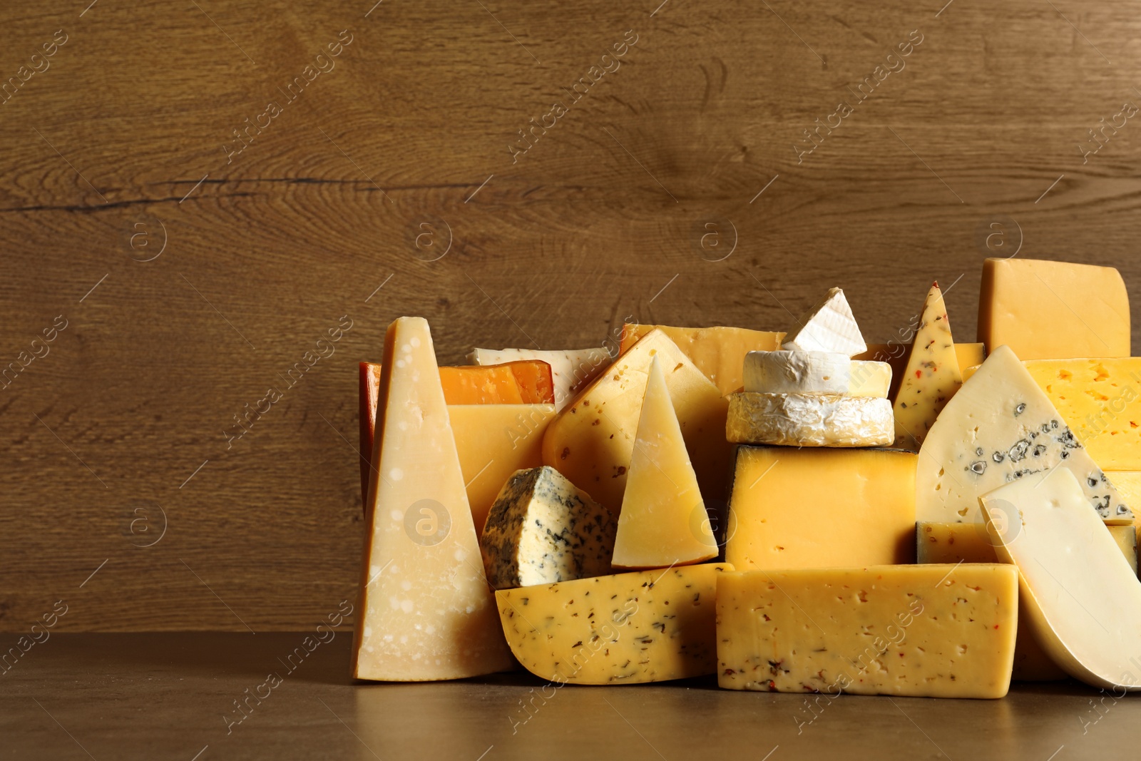 Photo of Different types of delicious cheese on table against wooden background