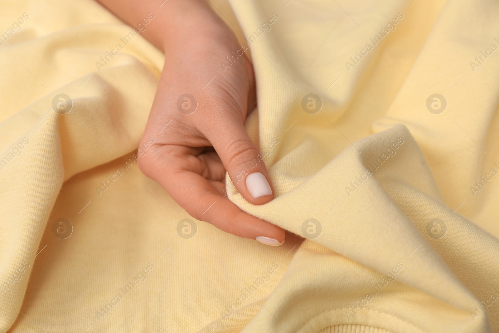 Photo of Woman touching soft yellow fabric, closeup view