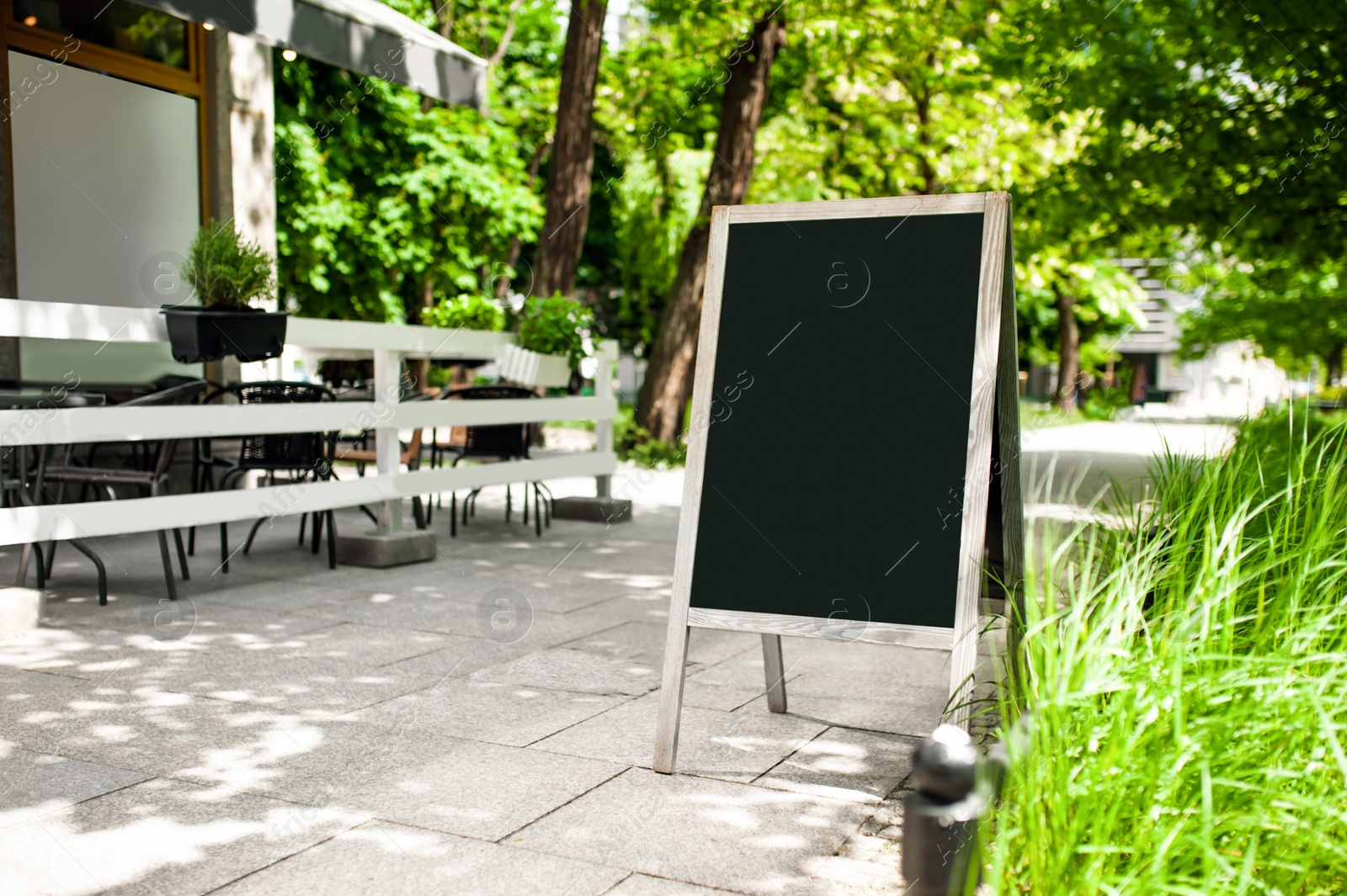 Photo of Blank advertising A-board near cafe. Mockup for design