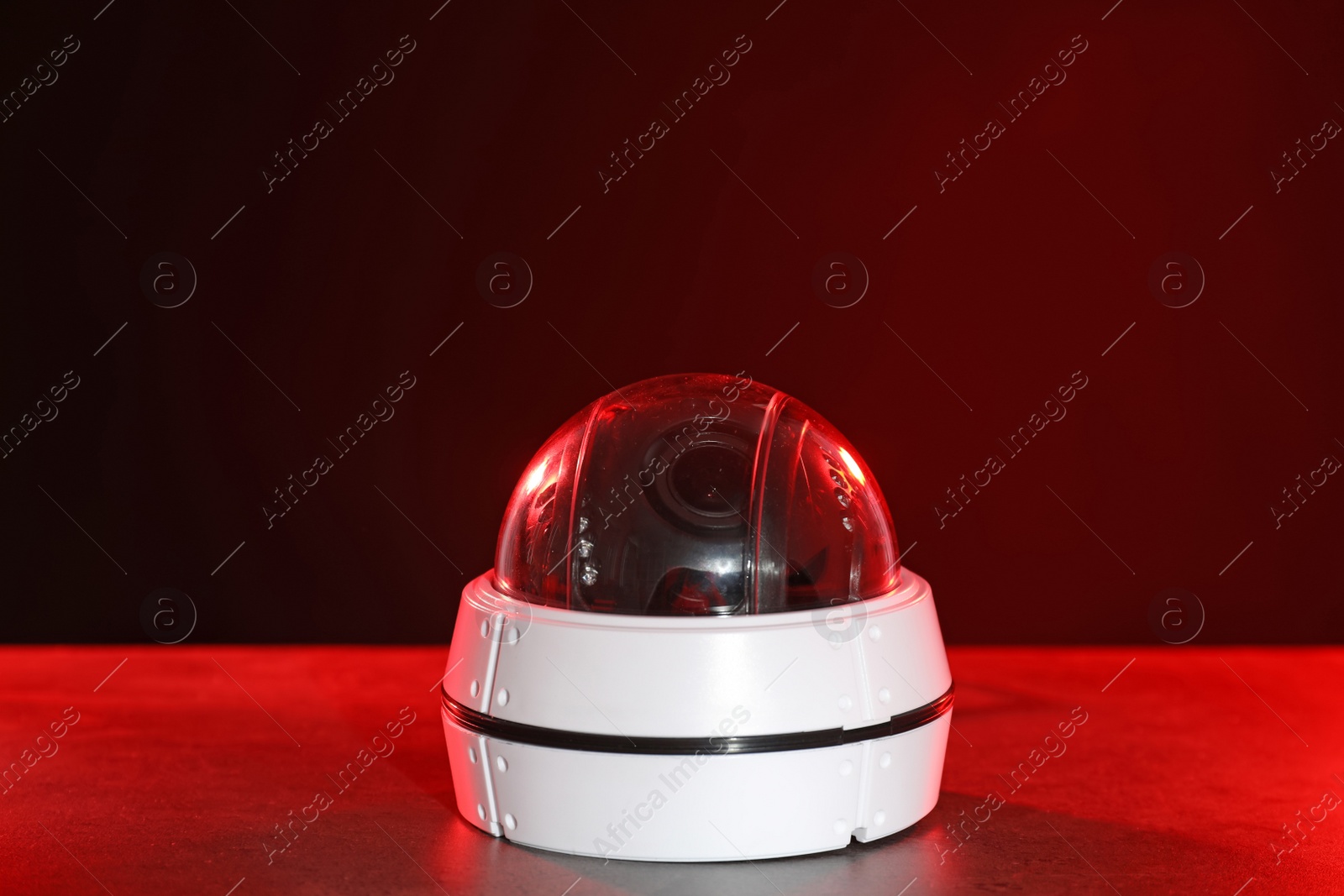 Photo of Modern security CCTV camera on table against dark background