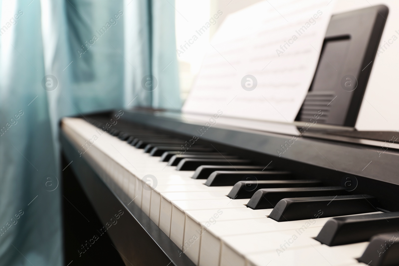 Photo of Modern piano with music sheets in room, closeup