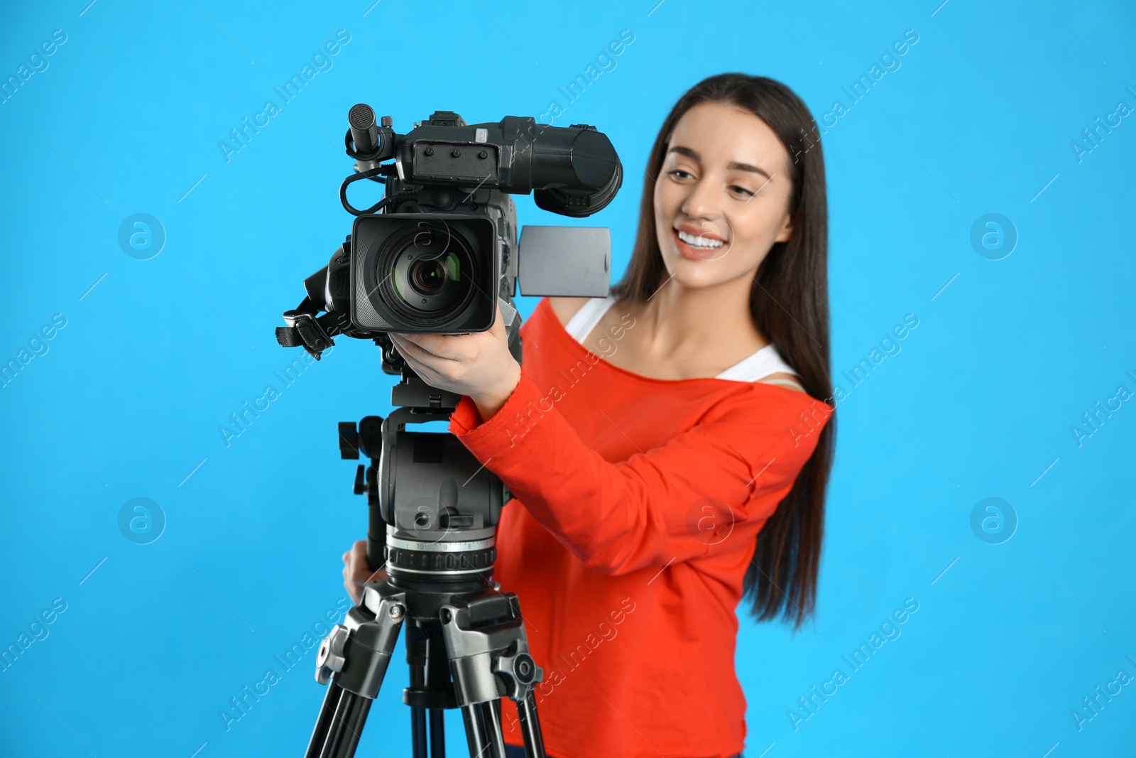 Photo of Operator with professional video camera on blue background