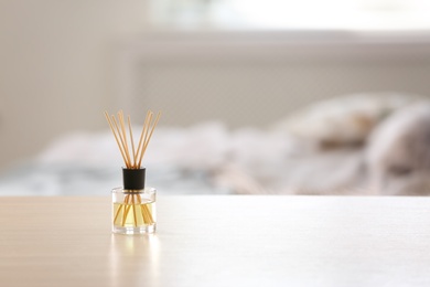 Aromatic reed air freshener on table against blurred background