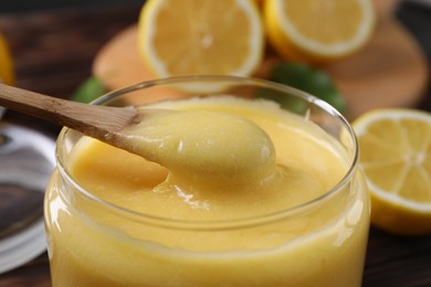 Taking delicious lemon curd from glass jar at table, closeup