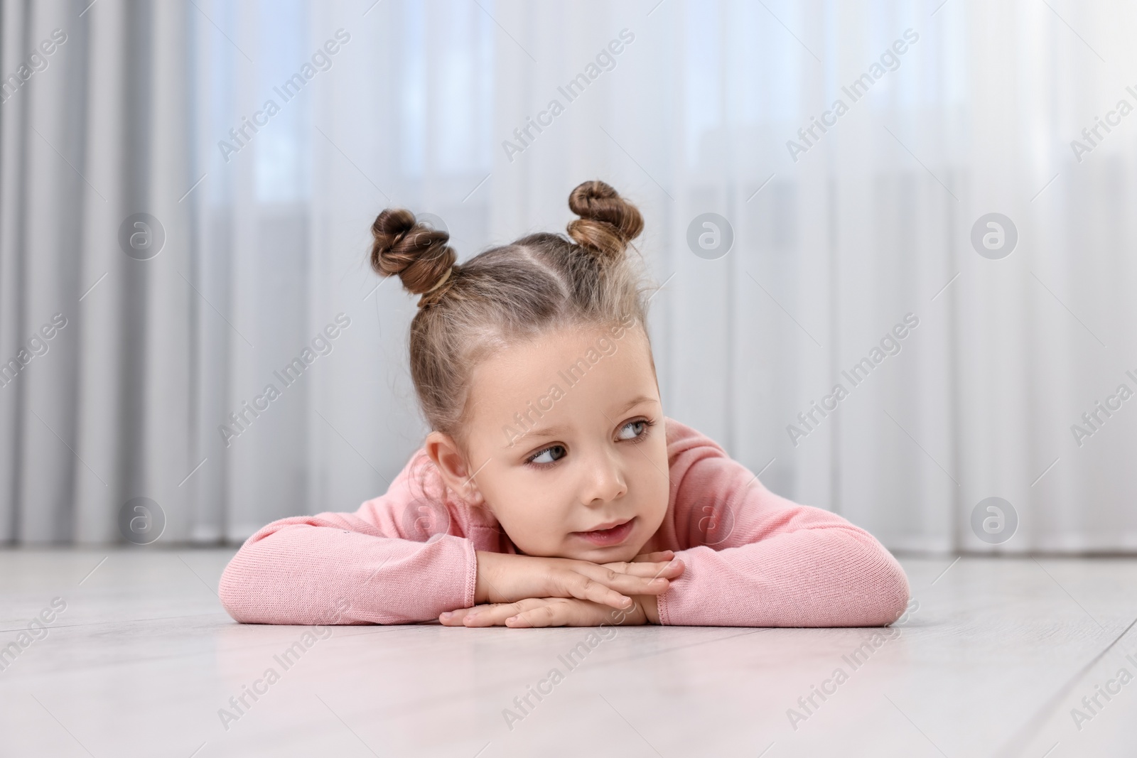 Photo of Cute little girl lying on warm floor at home. Heating system