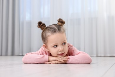 Photo of Cute little girl lying on warm floor at home. Heating system