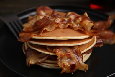 Photo of Delicious pancakes with fried bacon served on wooden table, closeup