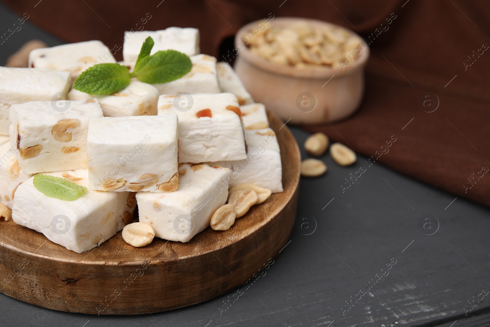 Photo of Pieces of delicious nutty nougat on wooden board, closeup