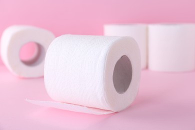 Photo of Soft toilet paper rolls on pink background, closeup