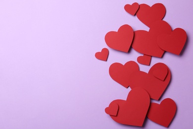 Photo of Red paper hearts on violet background, flat lay. Space for text