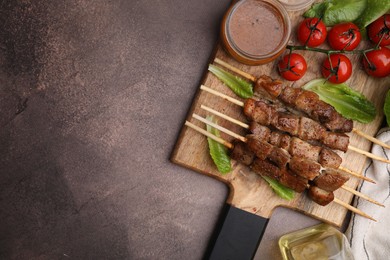 Photo of Tasty cooked marinated meat served with sauce and tomatoes on grey table, flat lay. Space for text