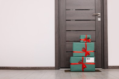 Christmas gift boxes on floor near door, space for text. Sending present by mail