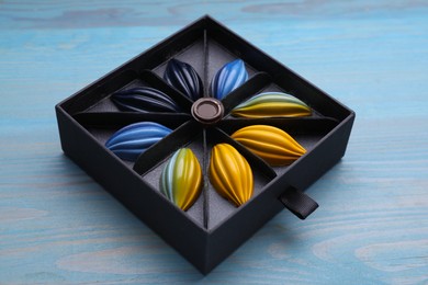 Photo of Box of tasty chocolate candies on light blue wooden table, closeup