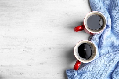 Photo of Flat lay composition cups of hot coffee and sweater on white wooden background, space for text. Winter drink