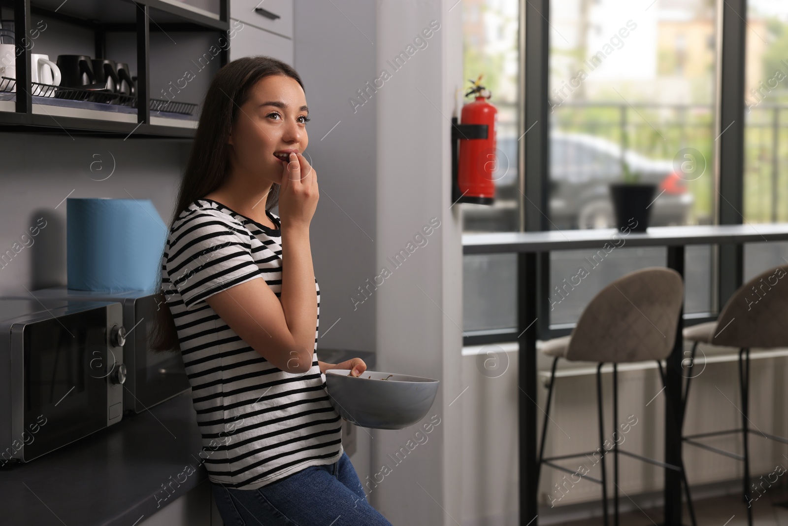 Photo of Young woman eating cherries in hostel kitchen