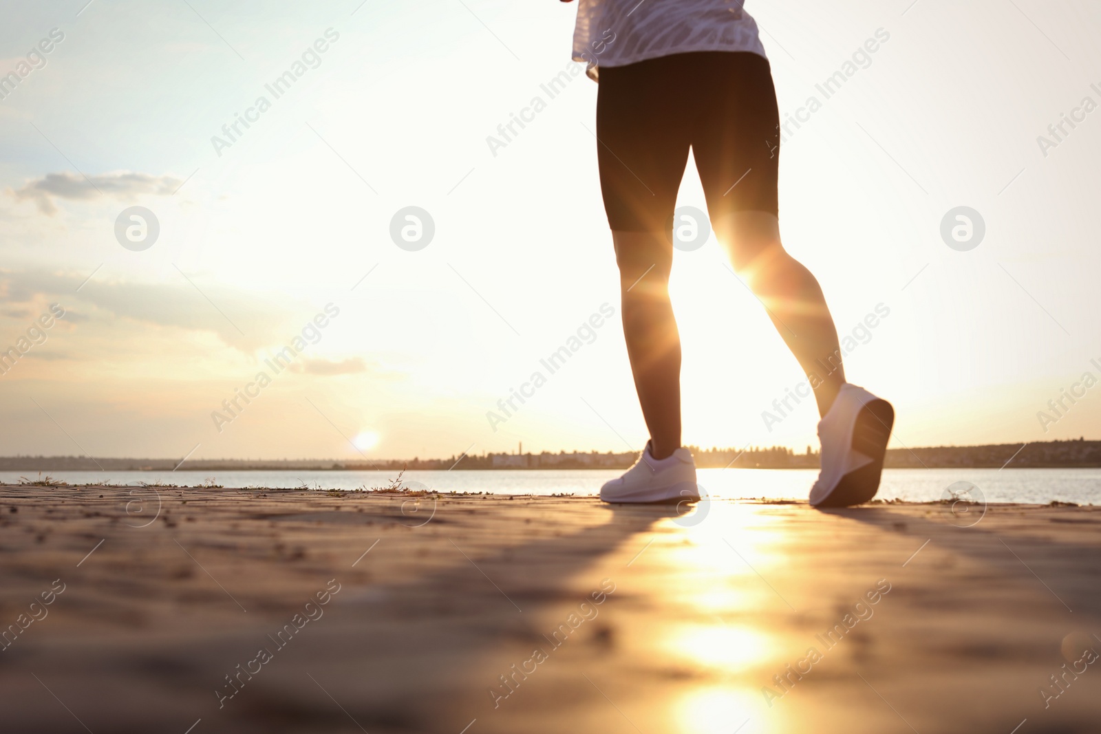 Photo of Young woman running near river in morning, closeup