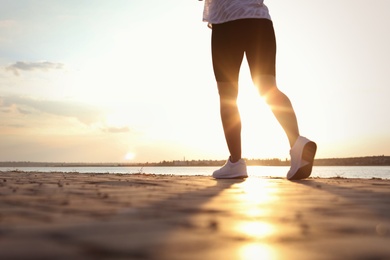 Young woman running near river in morning, closeup