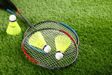 Photo of Badminton rackets and shuttlecocks on green grass outdoors, space for text
