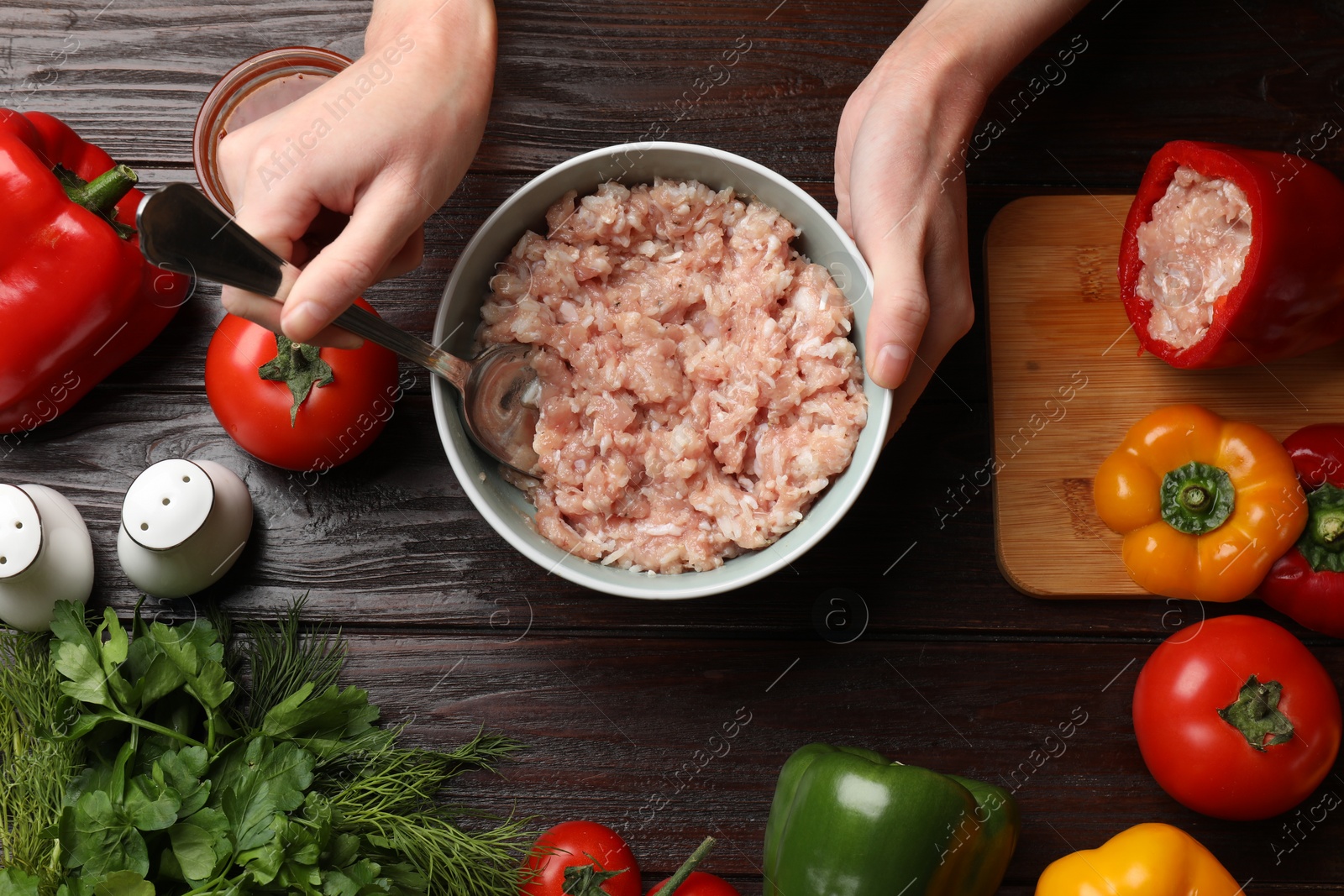 Photo of Woman making stuffed peppers with ground meat at wooden table, top view