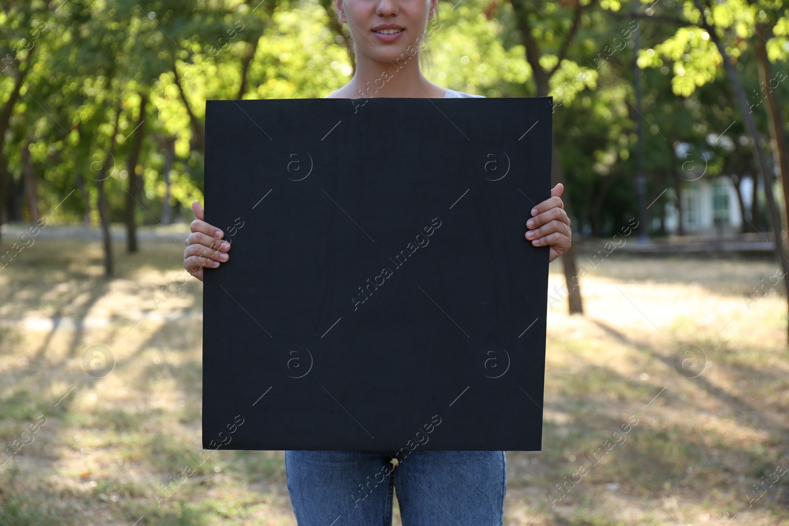 Photo of Woman holding blank poster outdoors, closeup. Mockup for design	