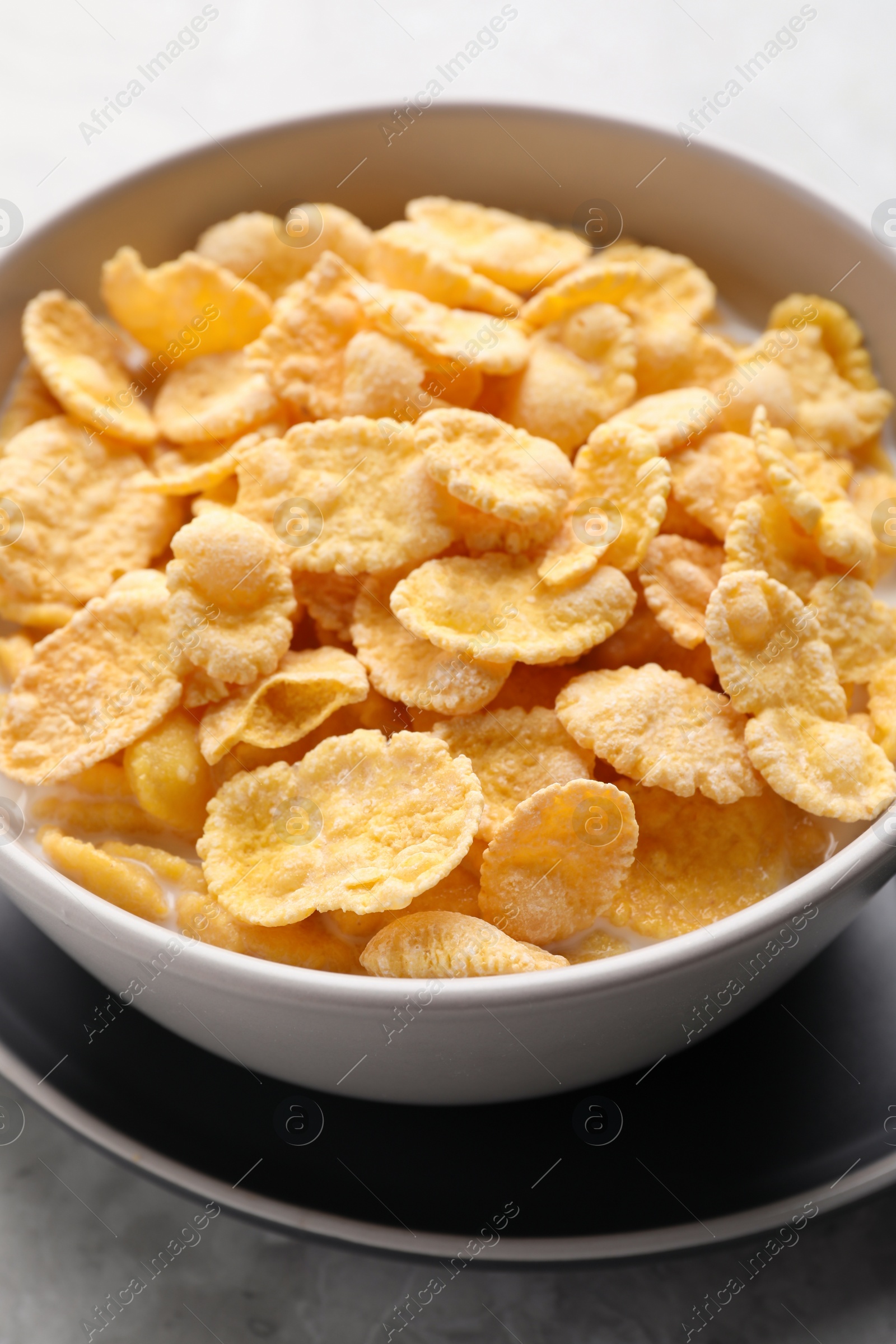 Photo of Tasty cornflakes with milk in bowl on table, closeup