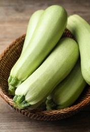 Photo of Basket of ripe zucchinis on wooden table, closeup