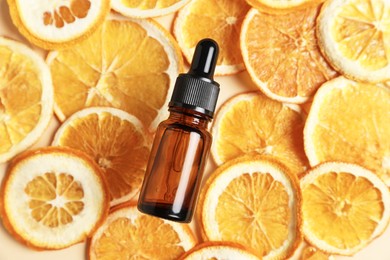 Photo of Bottle of organic cosmetic product and dried orange slices on beige background, flat lay