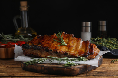 Photo of Tasty grilled ribs with rosemary on wooden table